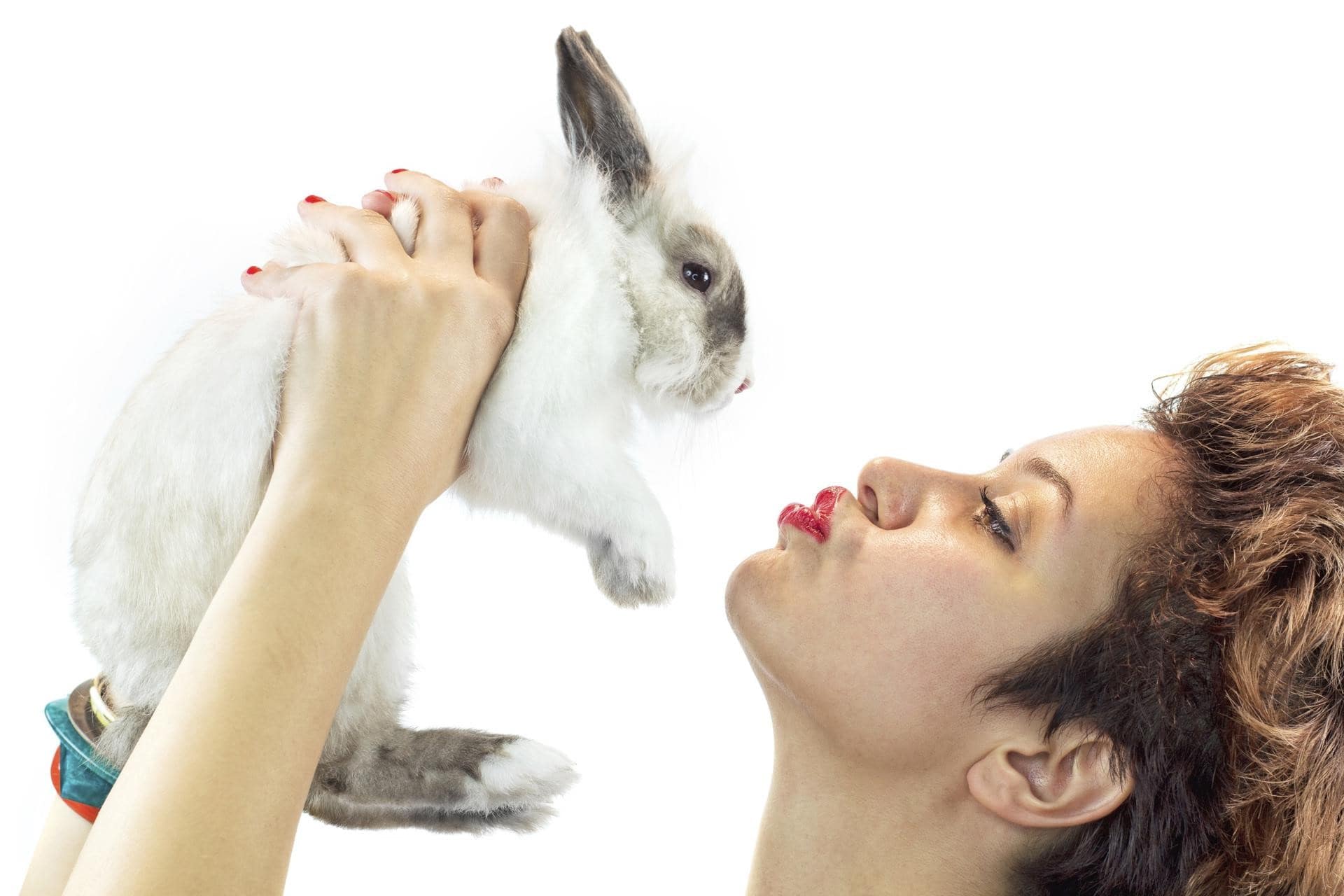 زنی با رژ و لاک قرمز رنگ، در حال بازی با یک خرگوش زیبا